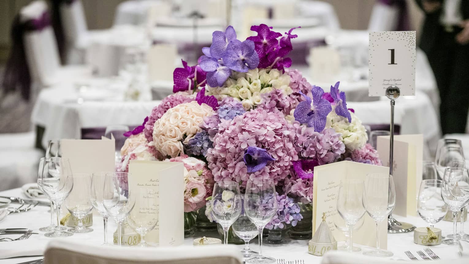 Wedding reception table setting with pink and purple floral centrepiece