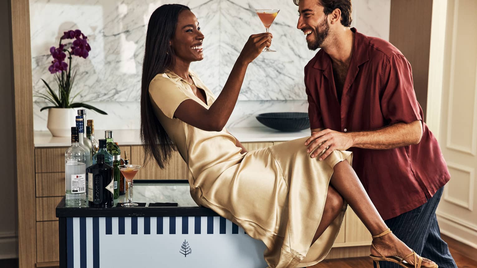 A man and woman by a cocktail cart.