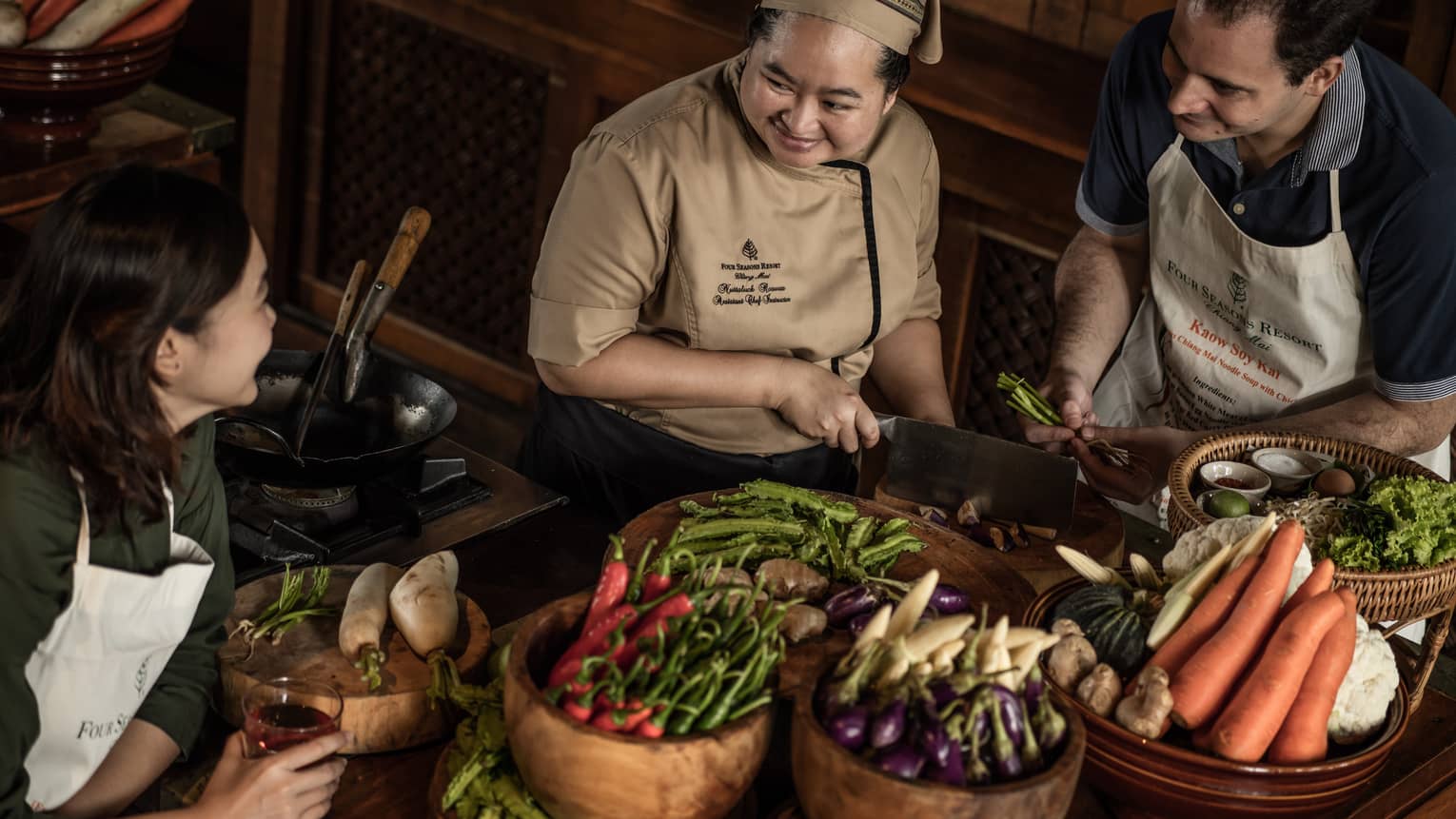 Chef chops mushrooms in front of couple, bamboo baskets with vegetables