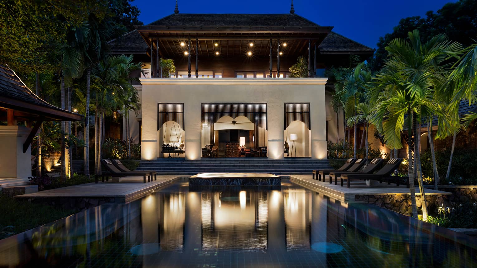 Large Four-Bedroom Residence Villa at night with lights, outdoor pool and palms 