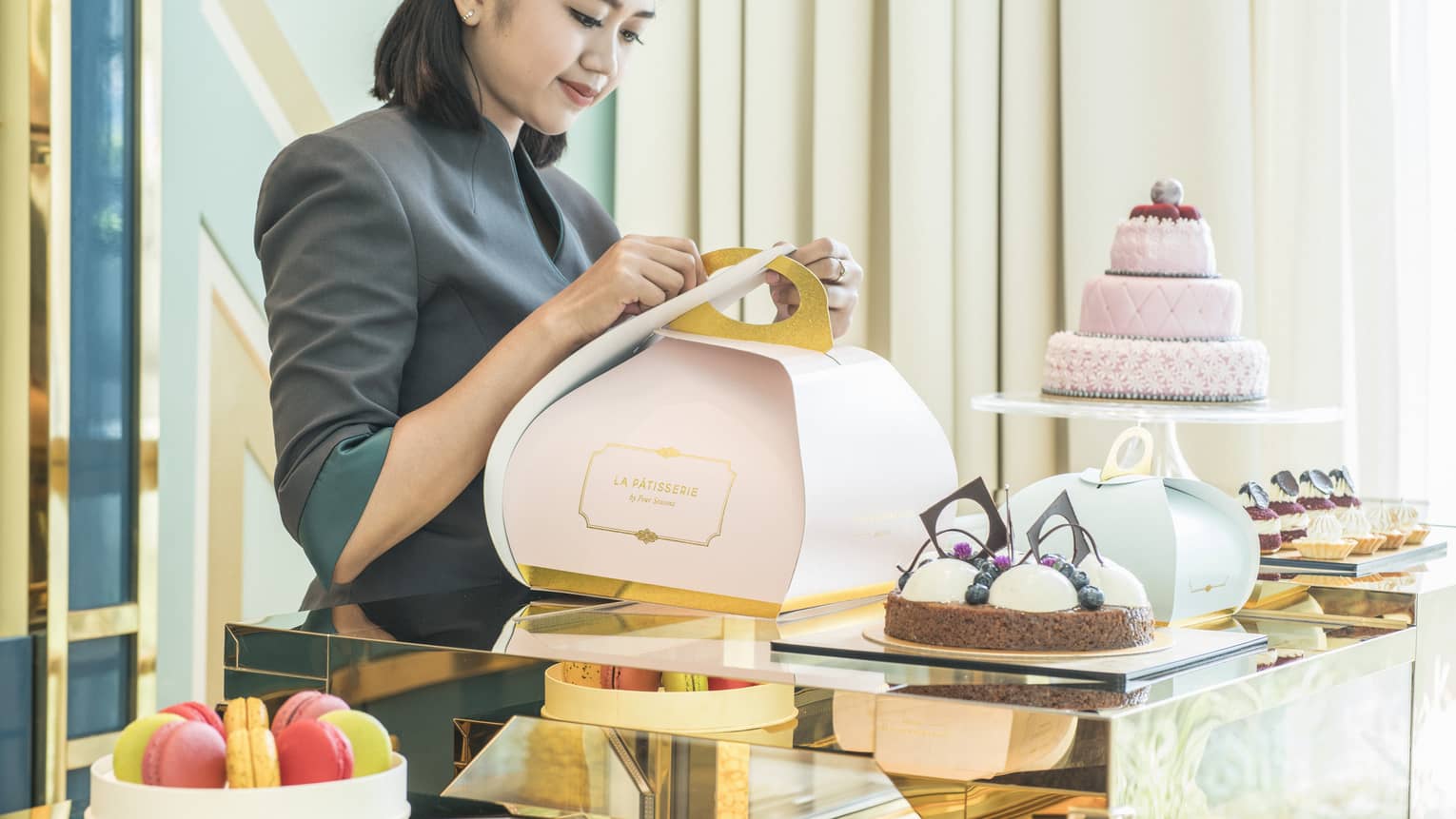 Woman wrapping a pastry in a stylish light pink box for take away