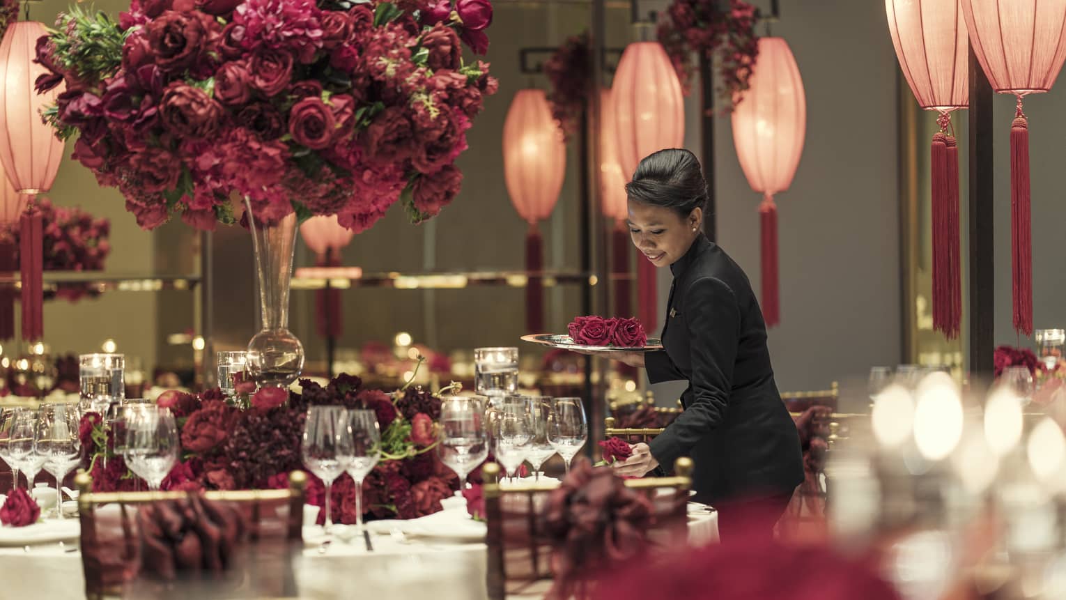Woman setting place setting for a Chinese wedding in the ballroom