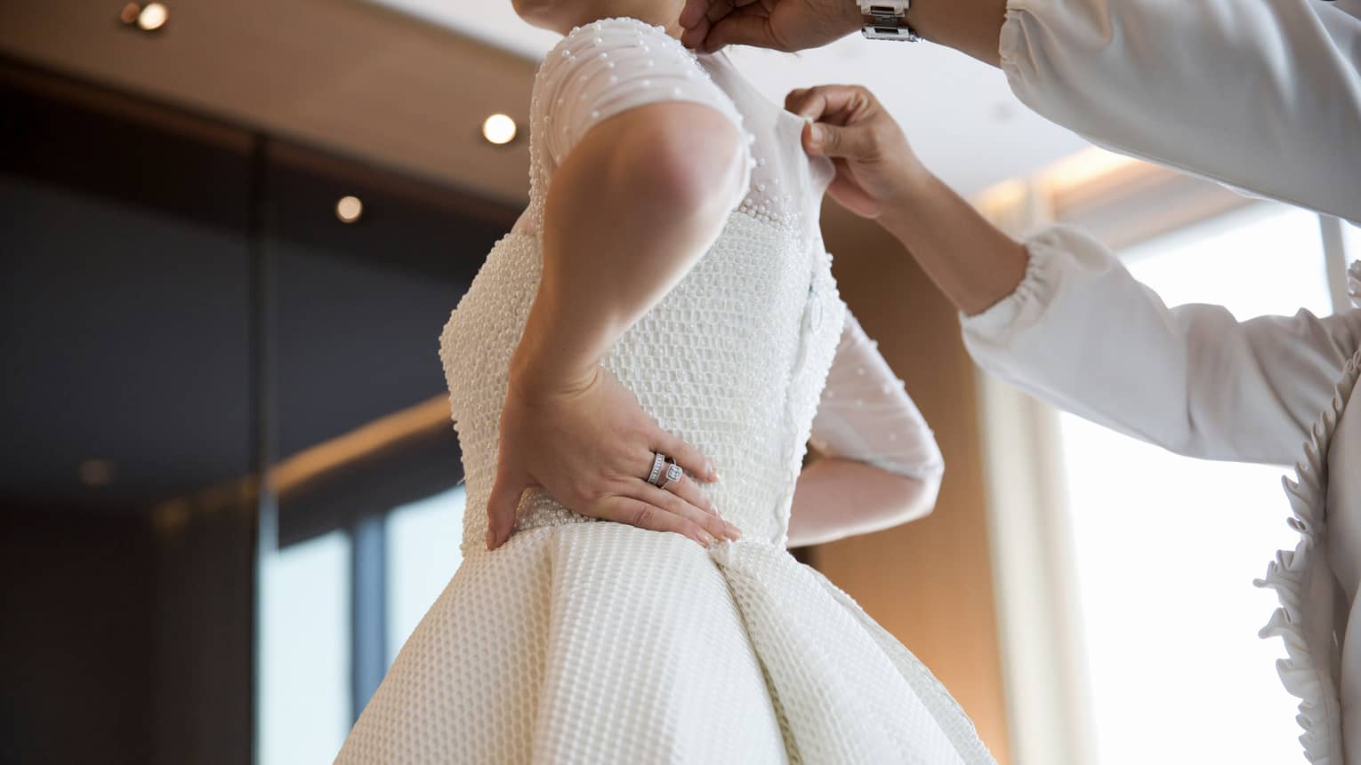 Person zips up bride's white wedding dress 
