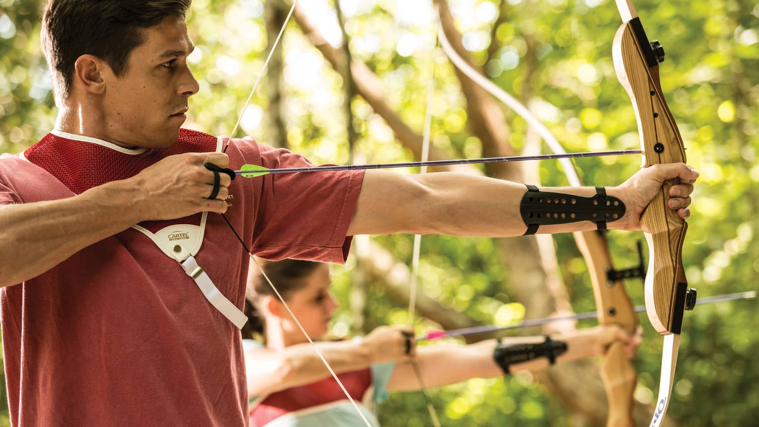 Man and woman hold bow and arrow, prepares to shoot