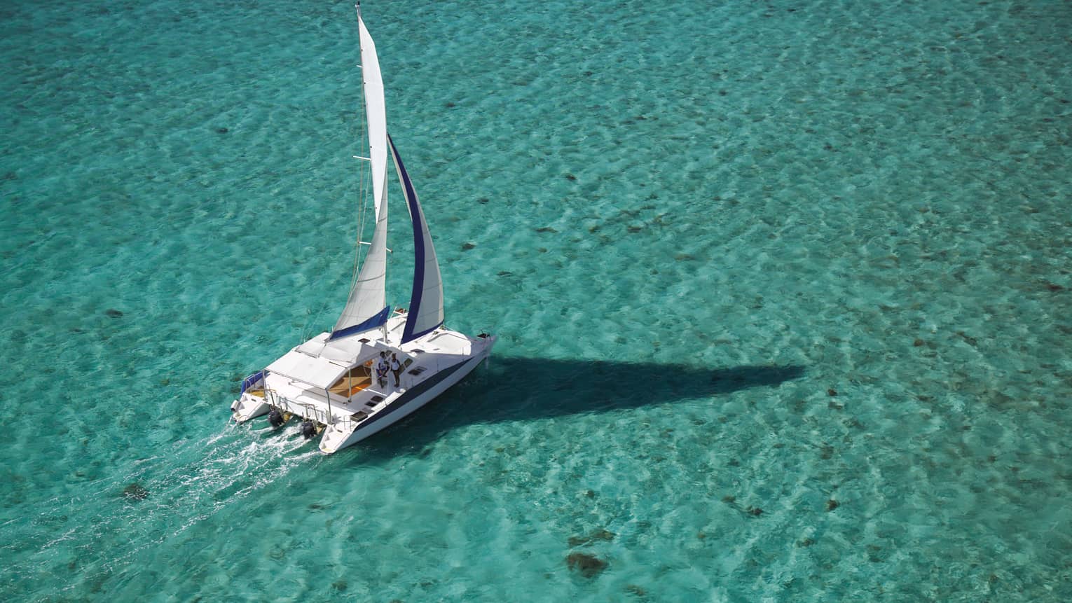 Aerial view of white yacht, sail on turquoise water in lagoon
