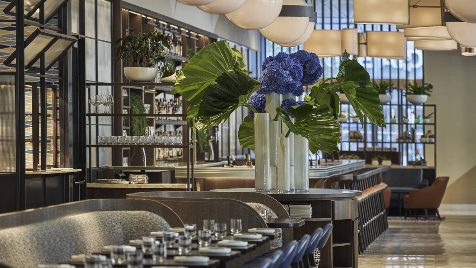 A long table is set with white porcelain plates and clear glasses at Vernick Restaurant in Four Seasons Philadelphia