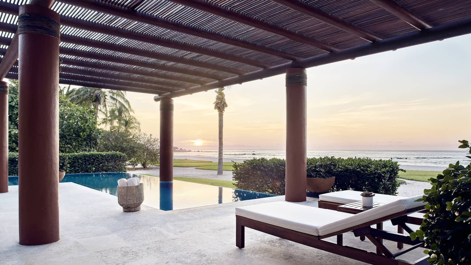 Outdoor terrace with lounge chairs, private pool, sun setting over the sea