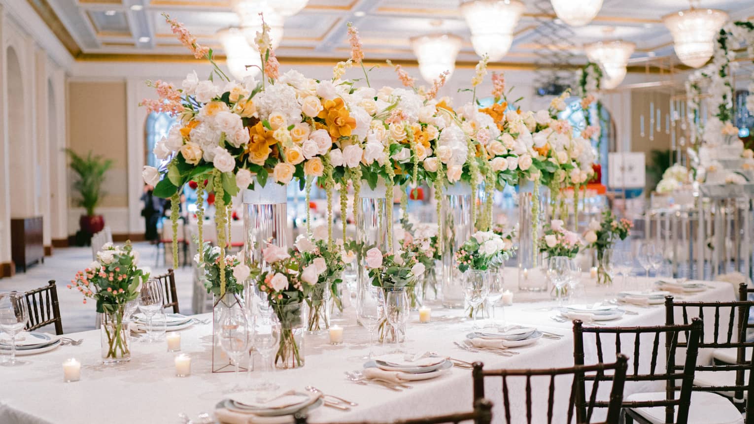 White, pink and orange roses in vases on wedding banquet dining table