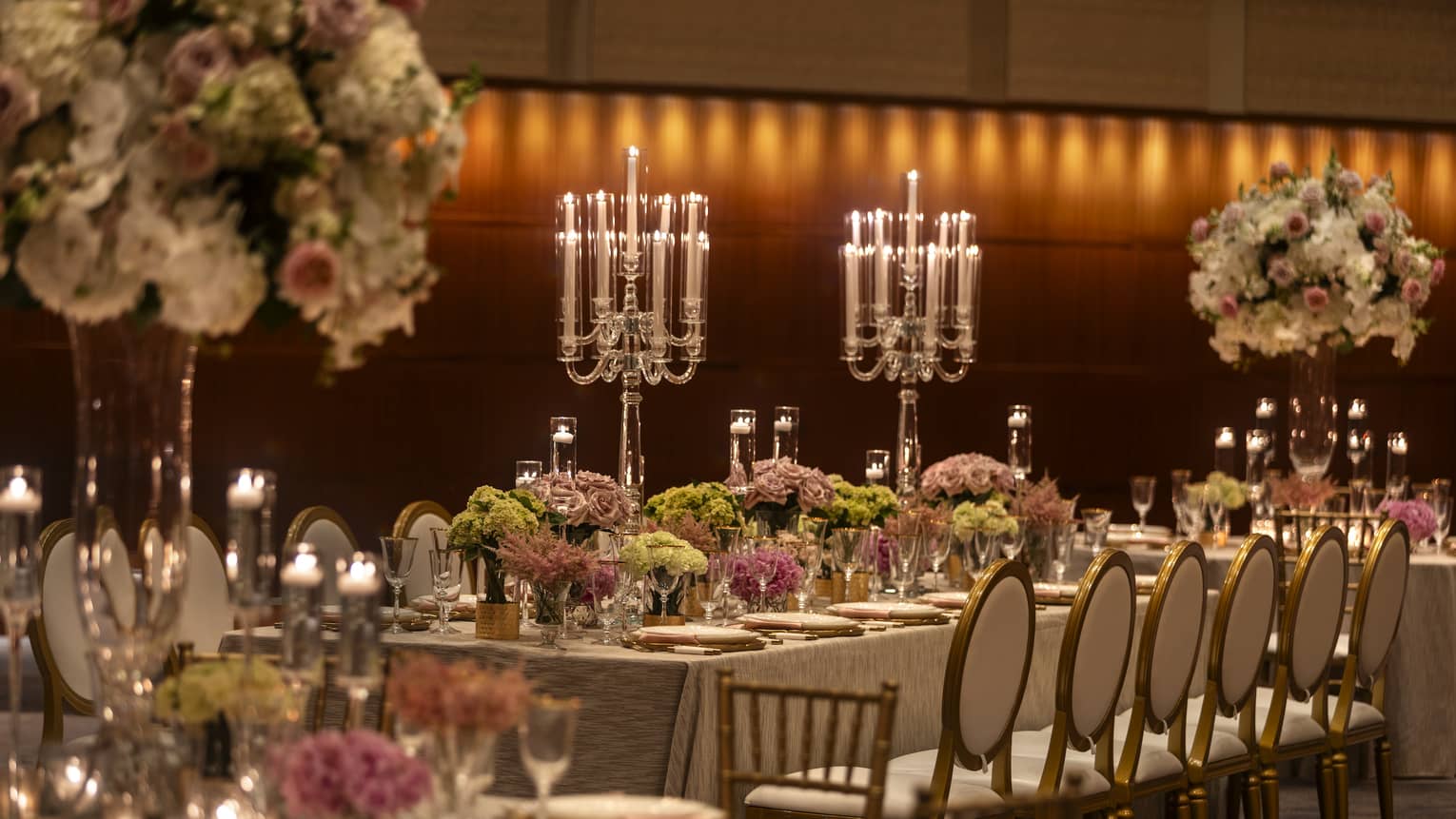 A ballroom with round and rectangular tables with flowers and candles.