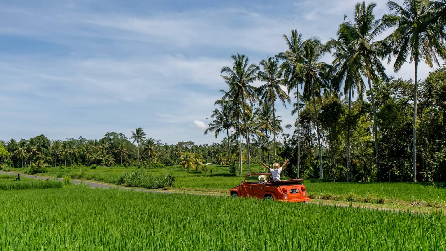 Couple driving orange Volkswagen through Bali countryside