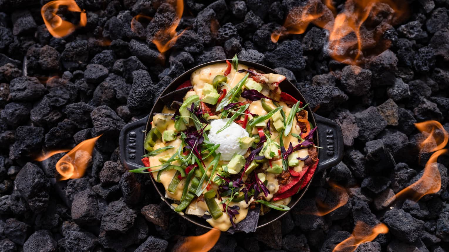 Dish with greens on charcoal with flames around it.