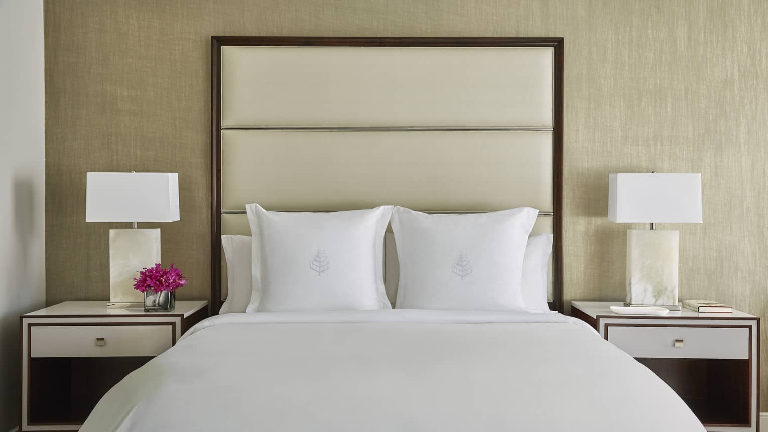 Deluxe Accessible Room head-on view of bed with white linens, tall padded beige headboard, nightstands with lamps