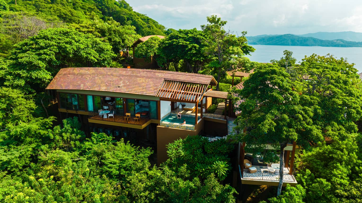 Private villa tucked away in a jungle canopy surrounded by greenery with the ocean in the distance