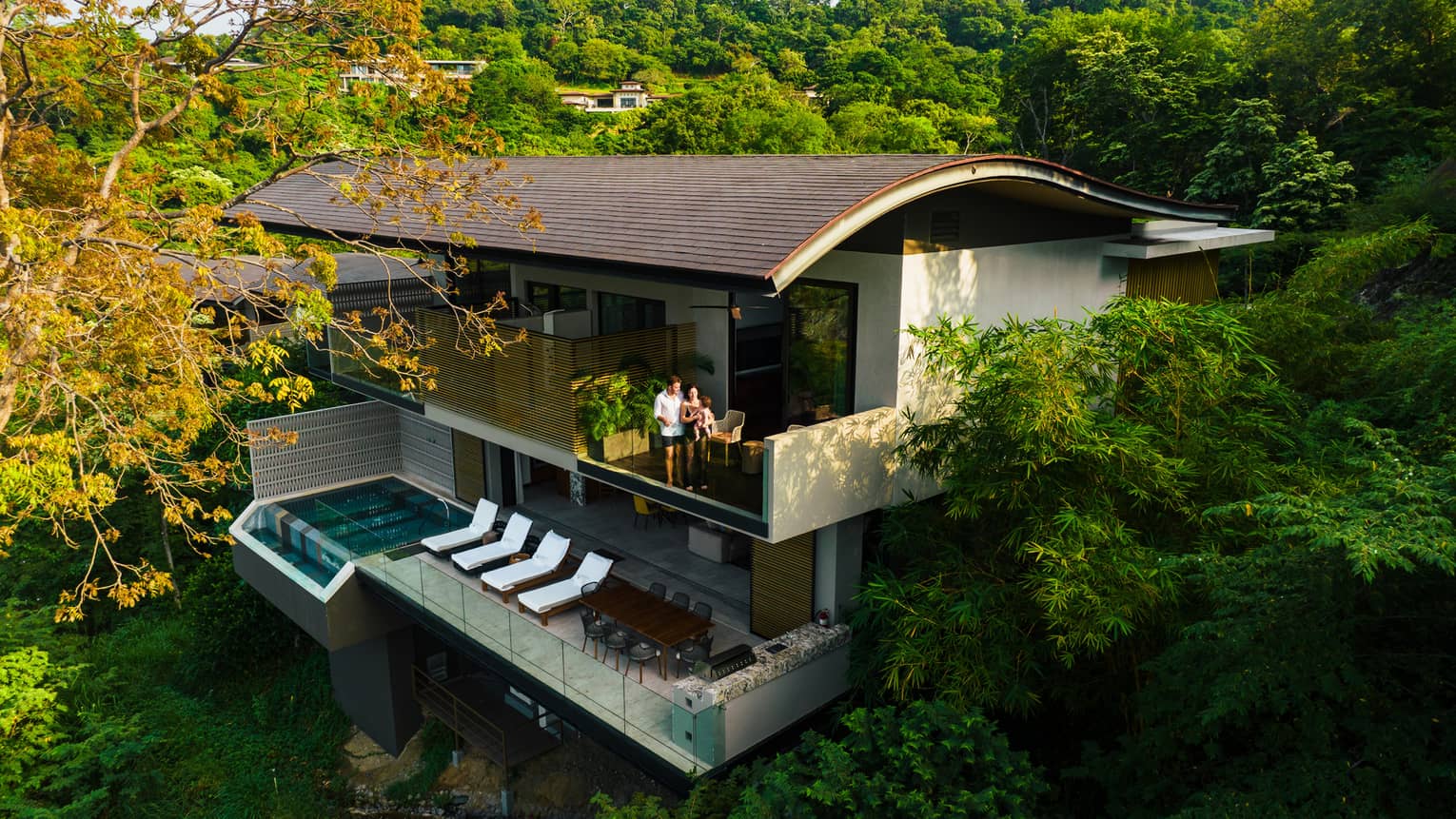 Two-level villa tucked into the jungle featuring a curved roof, multiple terraces and an outdoor pool and deck