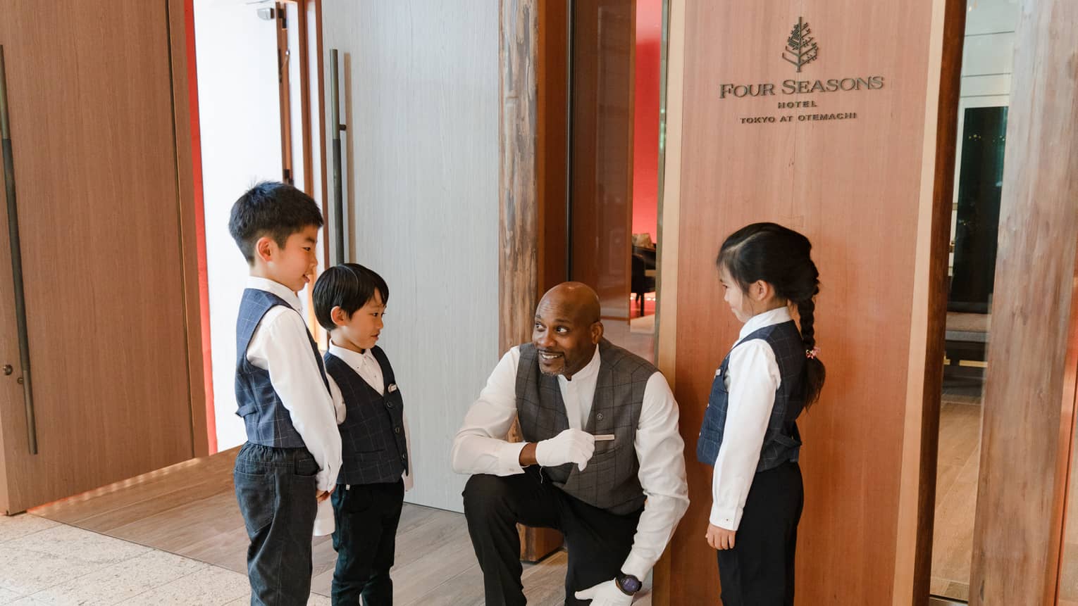 Three kids chat with a Door Attendant at Kids Academy