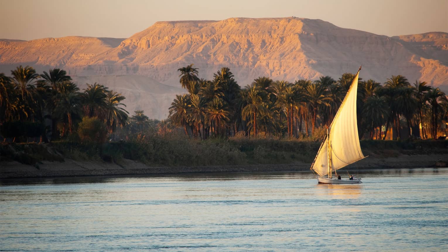 Traditional felucca wooden sailboat on the Nile at sunset 