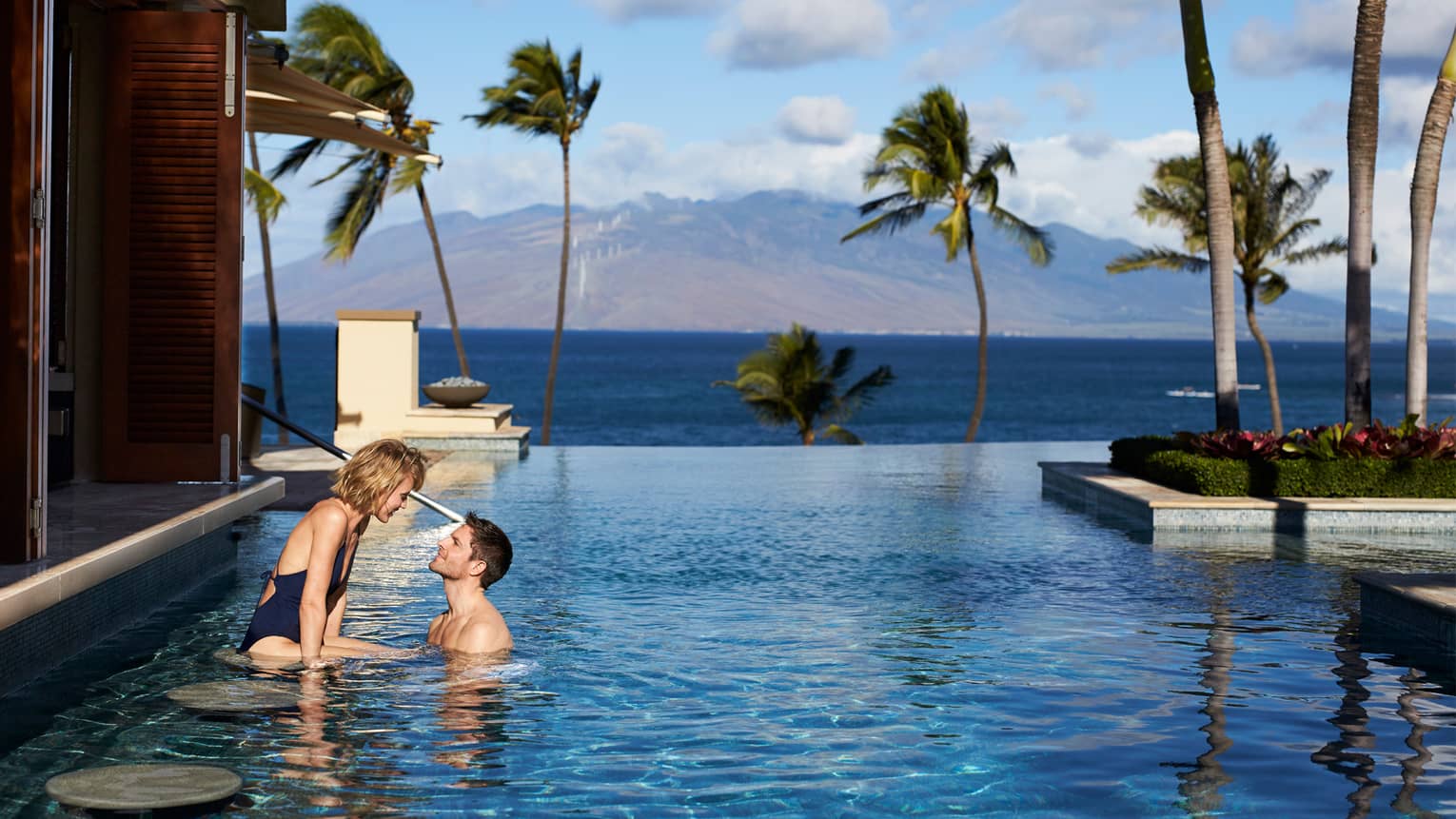 Man and woman at stools of swim-up bar in Serenity Pool, views of Lanai and the West Maui Mountains
