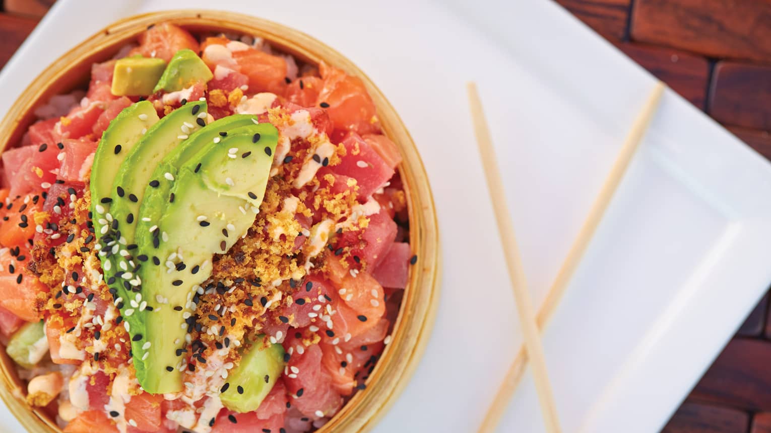 A poke bowl is topped with avocado slices and sesame seeds 