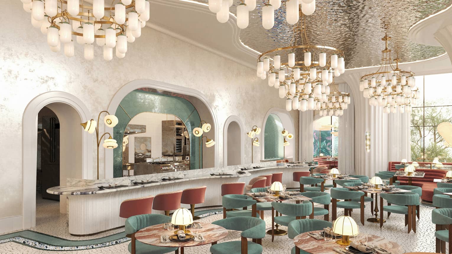 Restaurant with hanging chandeliers, emerald-green chairs and marble tables