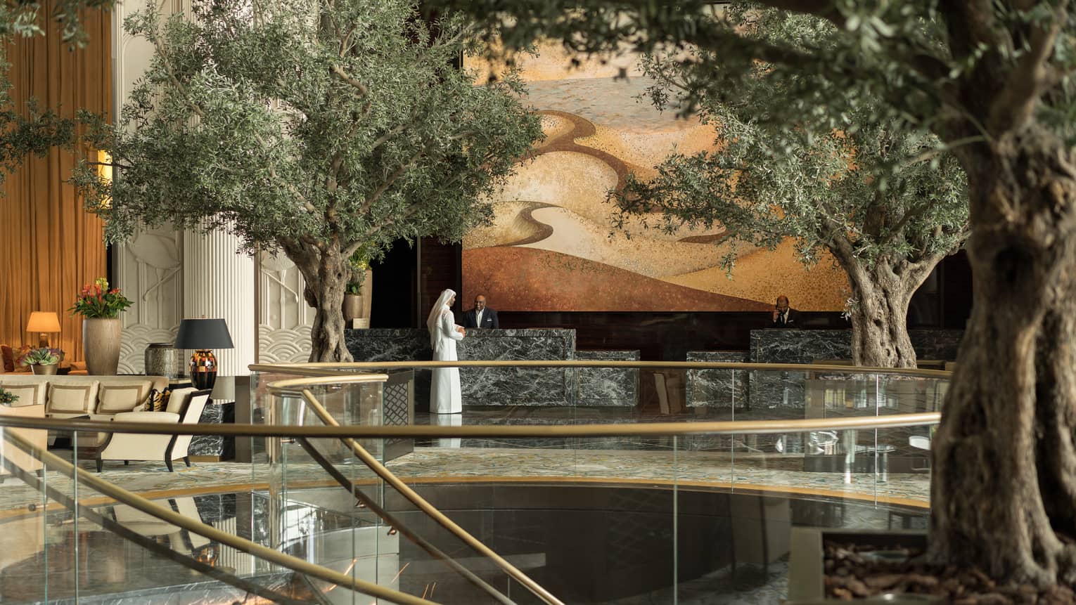 The lobby area featuring several live trees, and a golden staircase. 