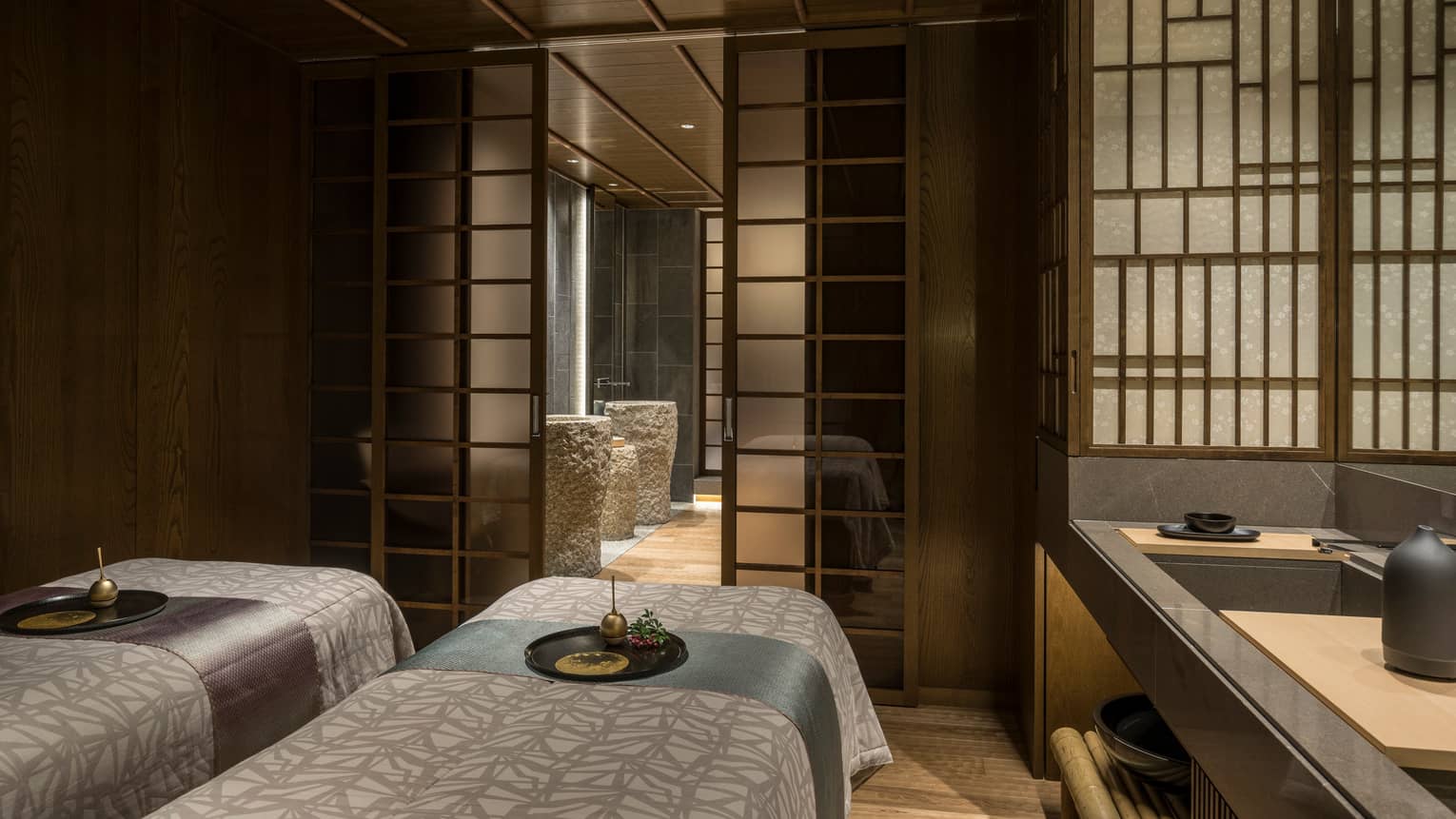 Couples massage beds in dark spa treatment room behind screen
