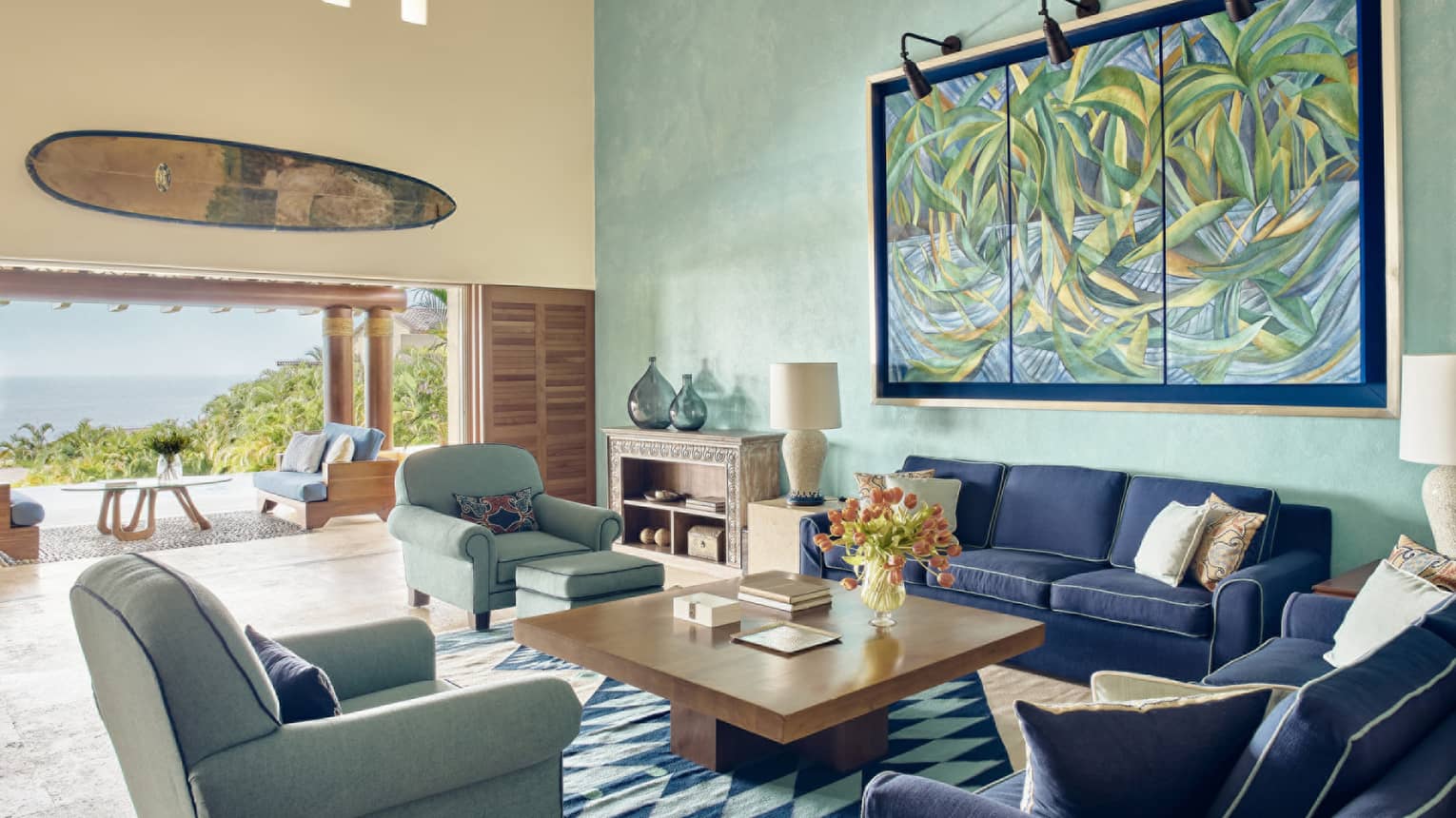 Living room with blue sofas, turquoise chairs and matching accent wall