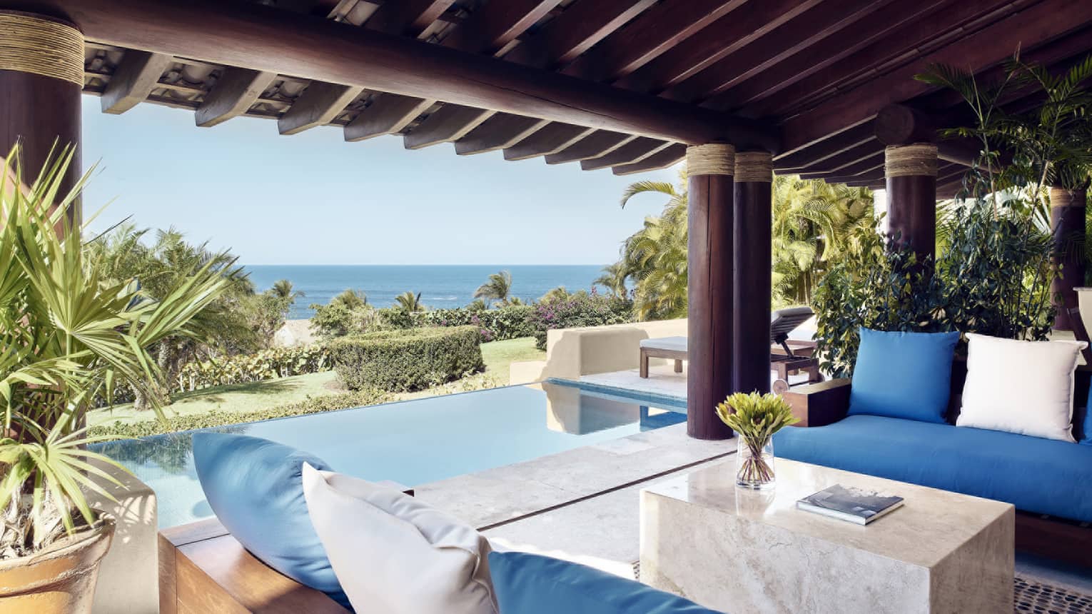 Covered outdoor lounge next to pool and ocean view