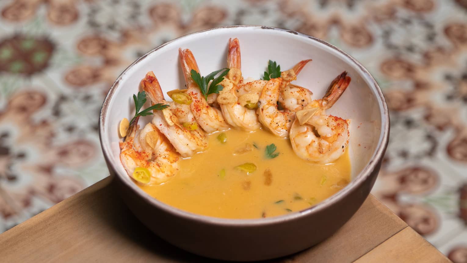 Shrimp in a yellow sauce served in a ceramic bowl.