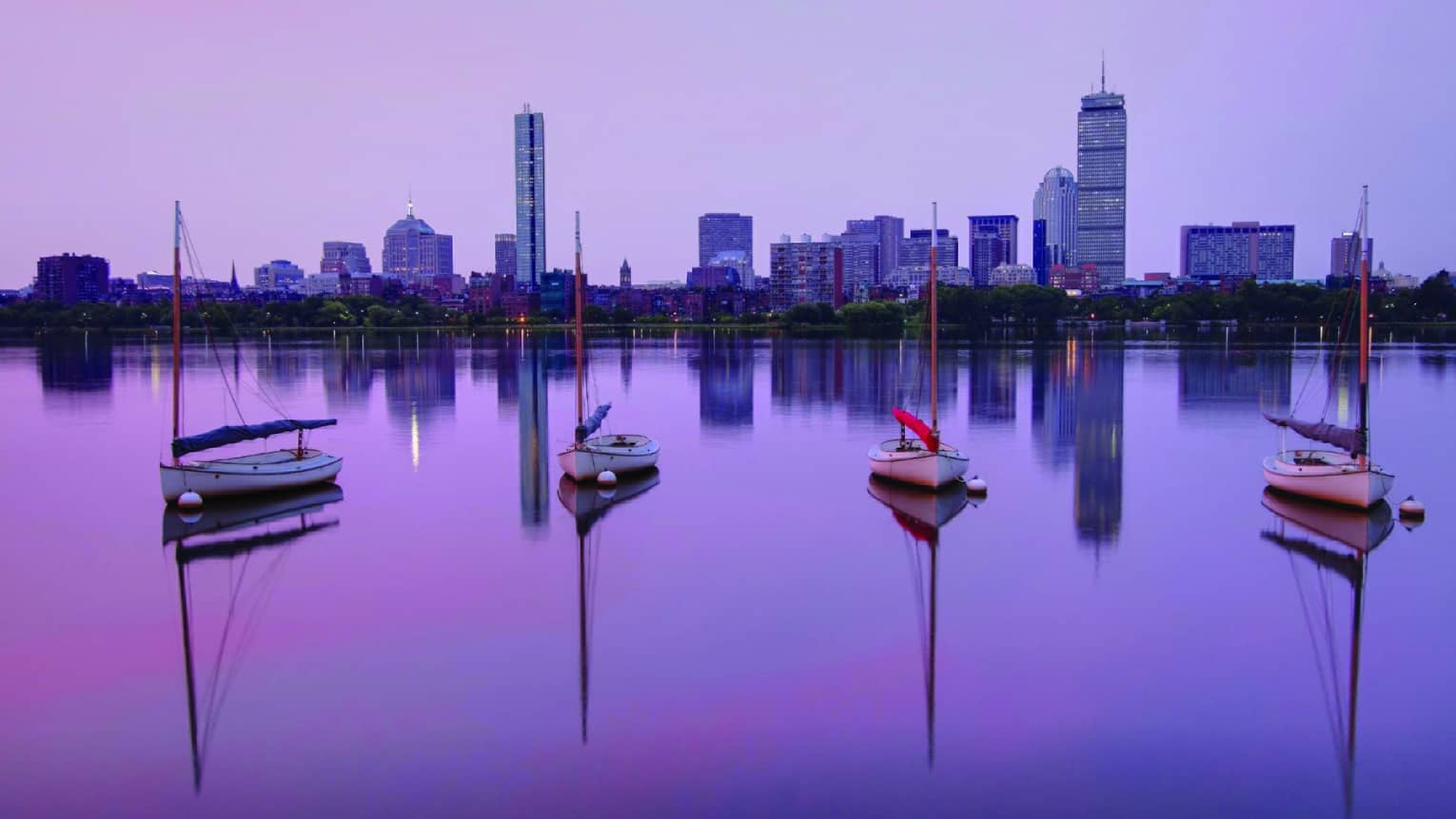 Sailboats parked on the Charles River, Boston skyline in background, purple sunrise 