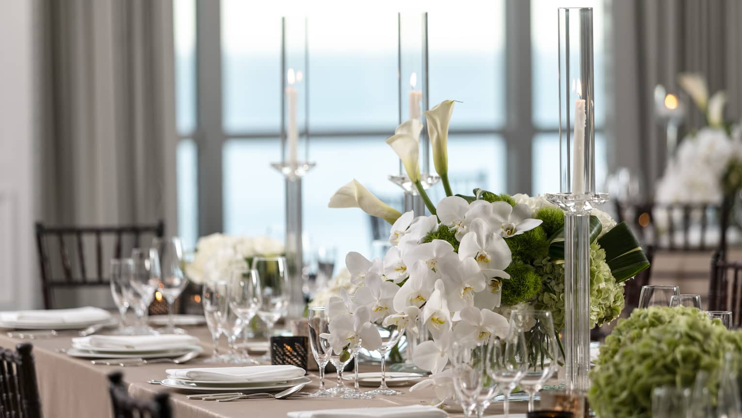 Part of formally set dining table with white orchids and tall crystal candlesticks