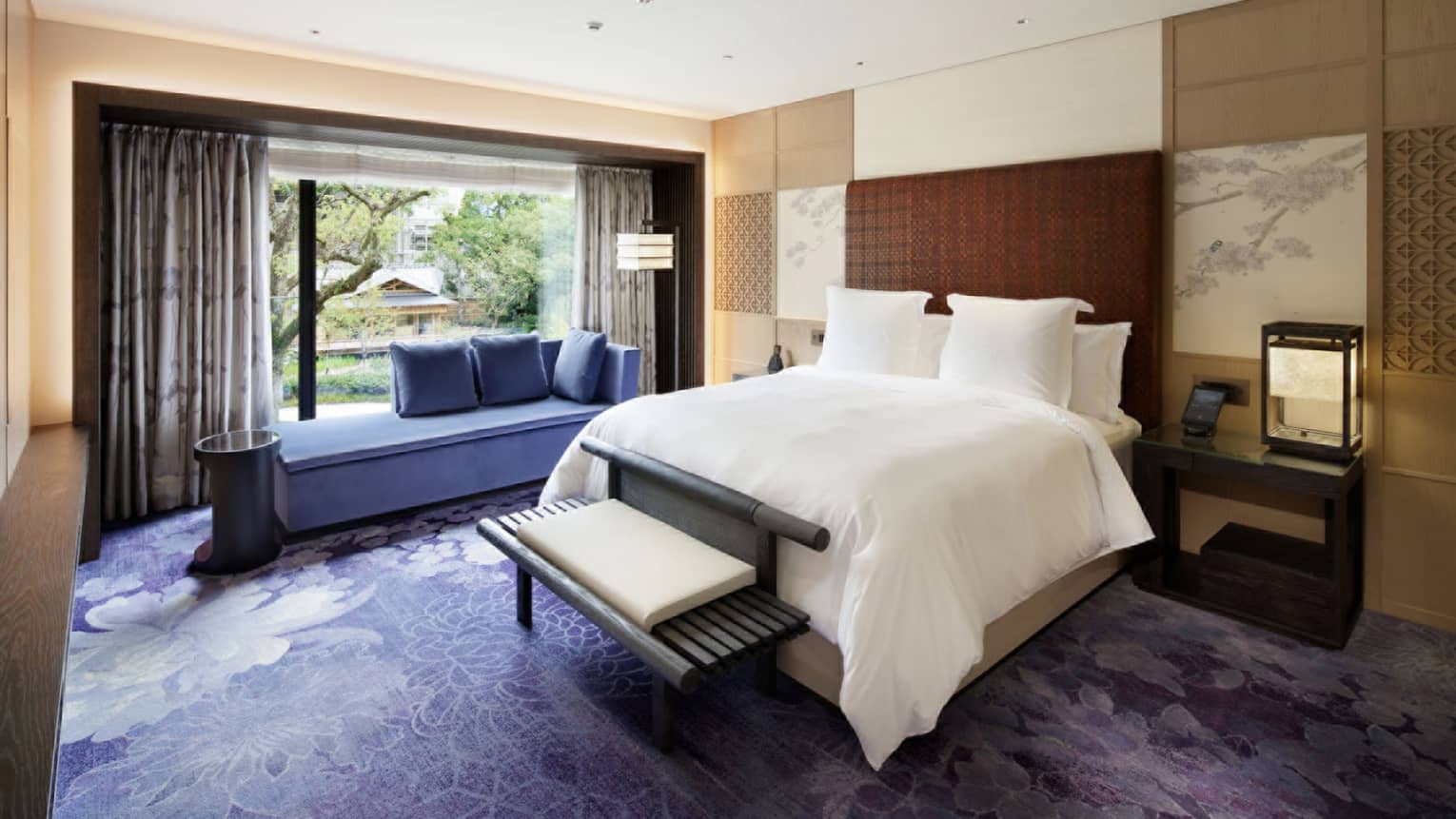 Bedroom with king bed, wooden bench, blue windowside chaise, purple carpet, Japanese wall art and window