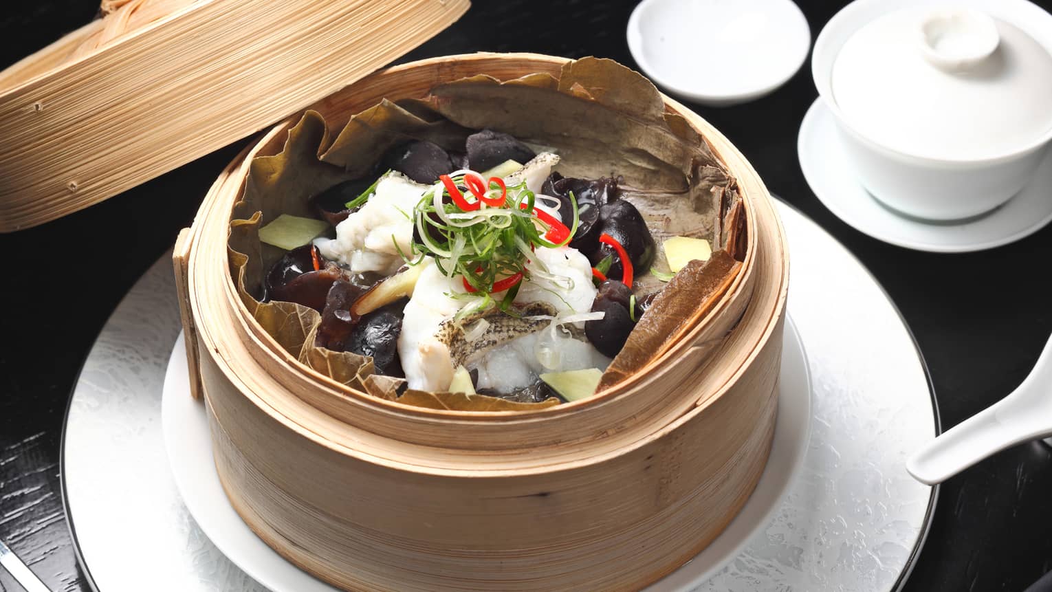 Bamboo steam basket with seafood, vegetables on white plate