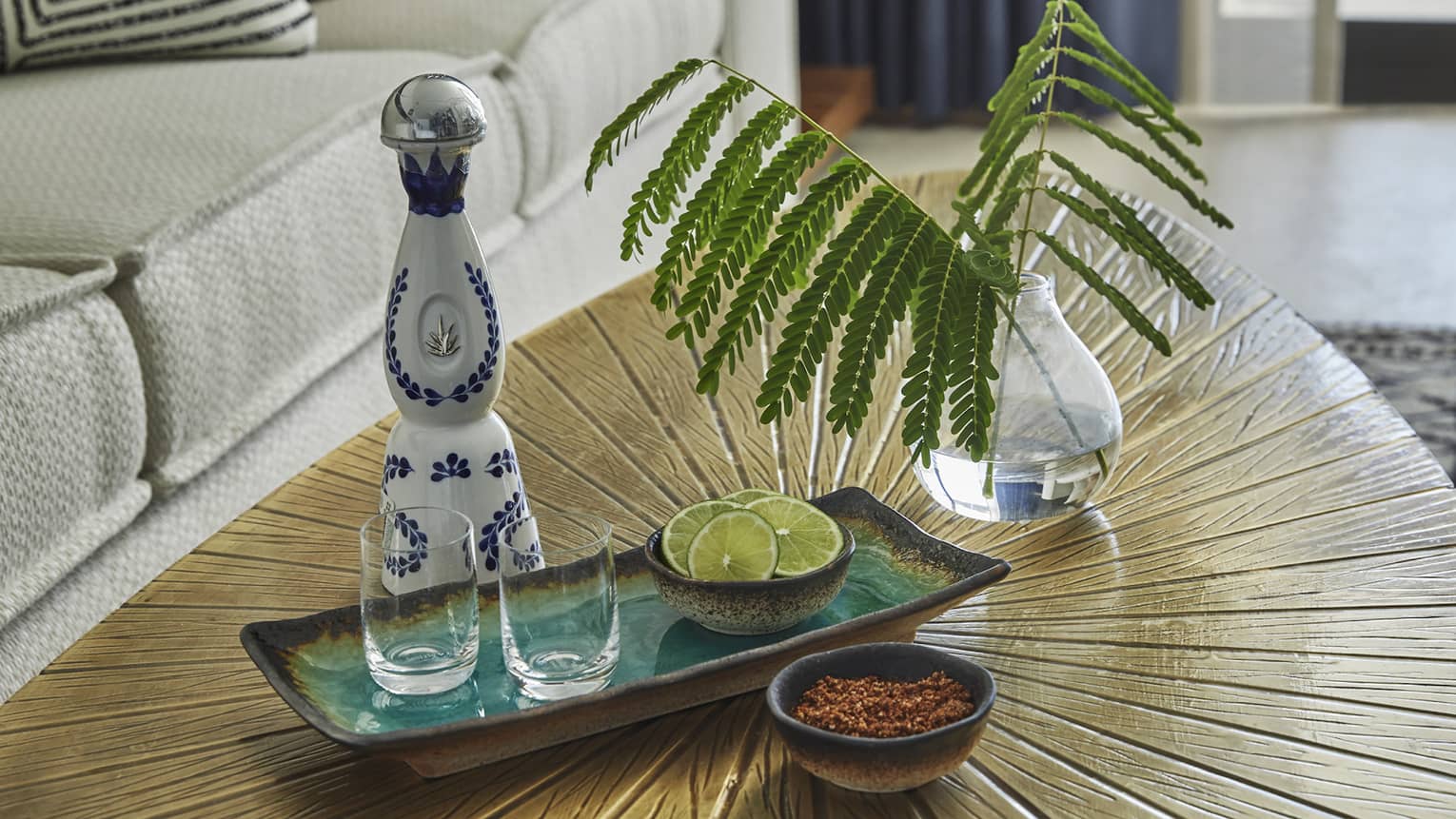 A coffee table with small glasses, a blue and white bottle and spices.