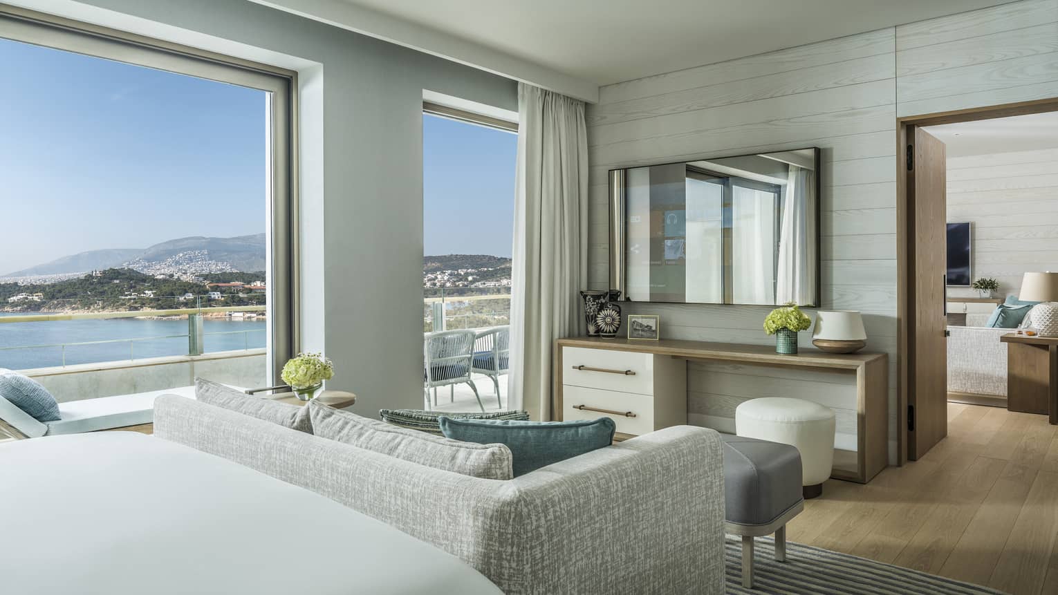 Arion One Bedroom Suite with bed, grey patterned loveseat, doorway to living area, ocean views
