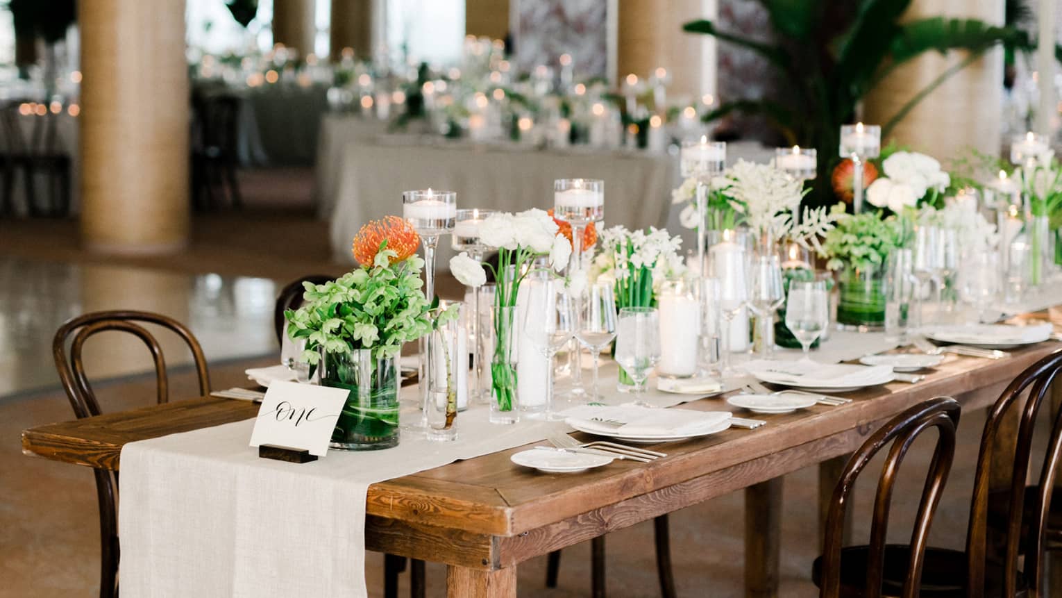 Event room with rustic wood dining table. table runner and flowers in vases