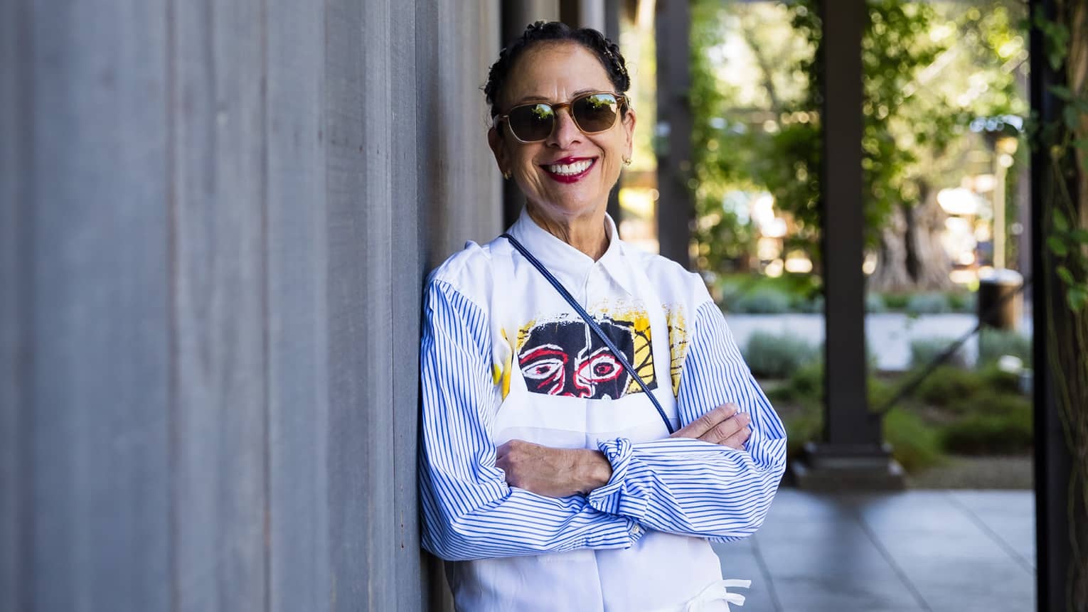 Nancy Silverton leaning against a building and wearing a chef?s coat.