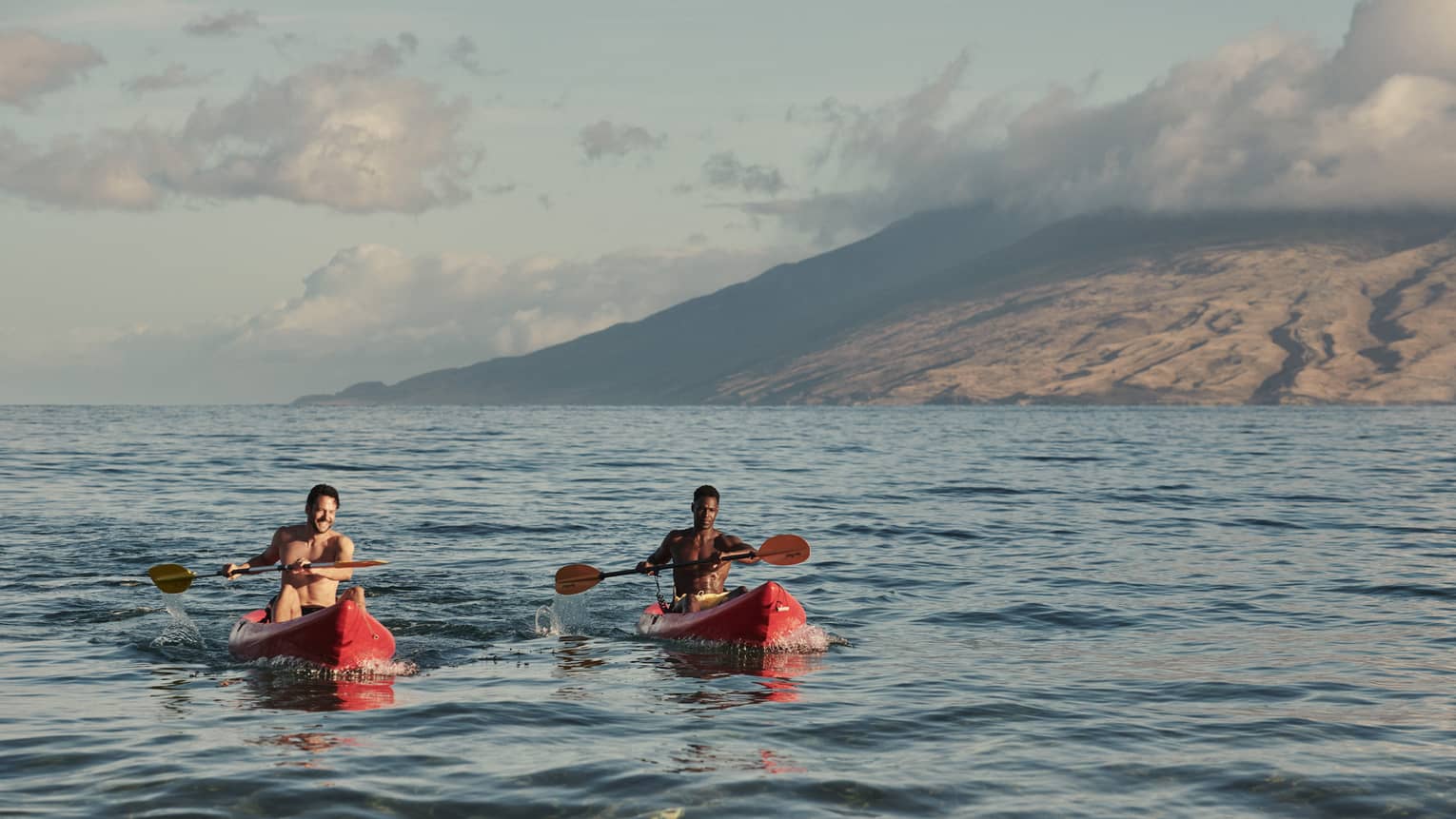 Two men in red kayaks in the ocean in Maui