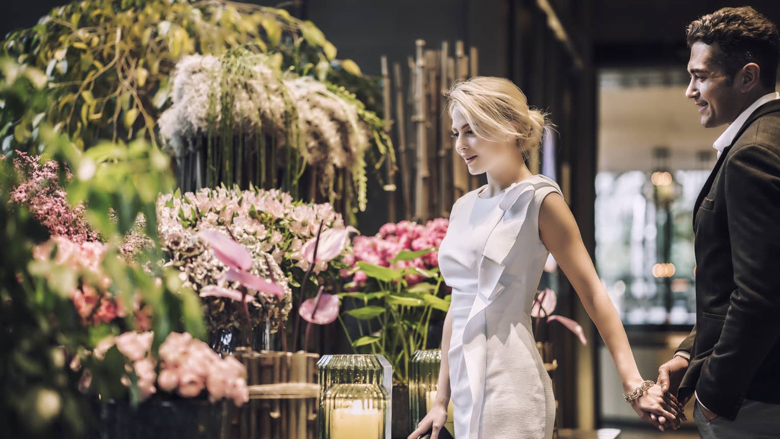 Woman and man admire large floral arrangements in hotel