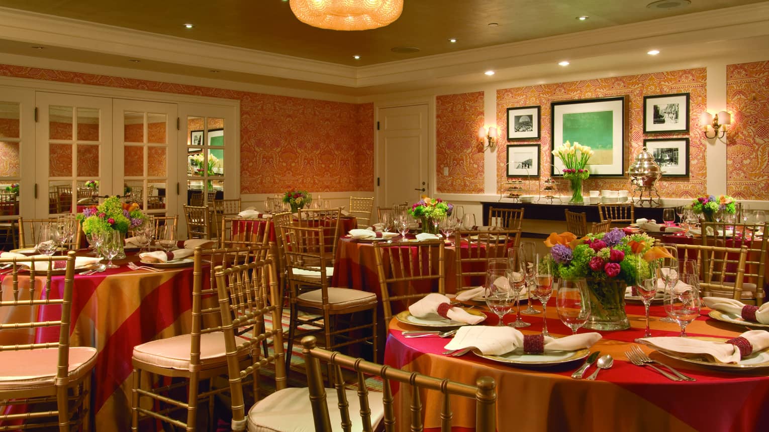 Round banquet tables with red and gold linens, flowers in Benjamin Room 