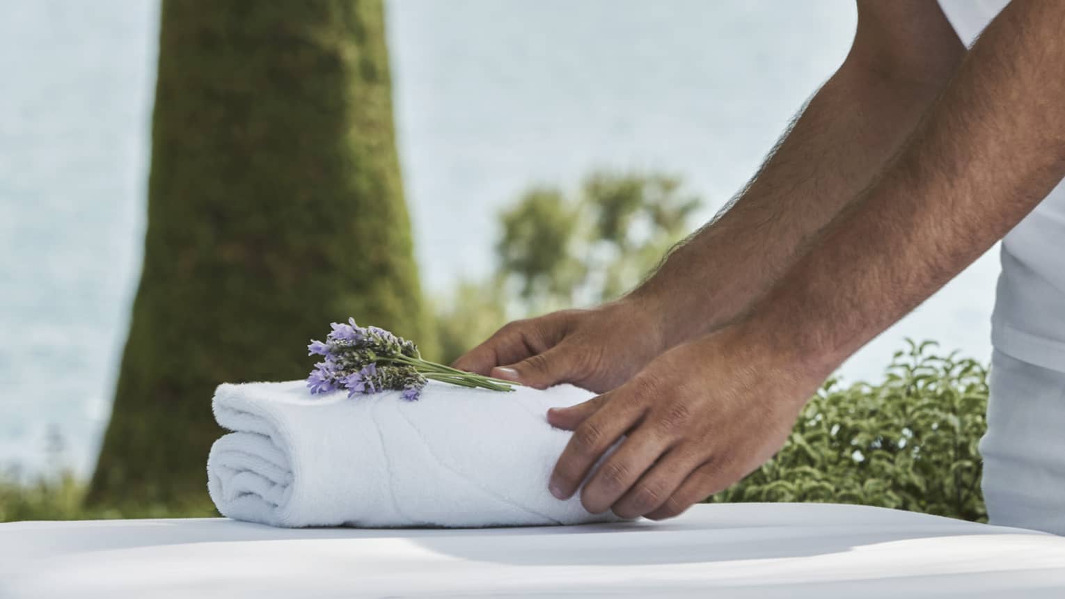 Close-up of hands setting on folded white towel with lavender sprig