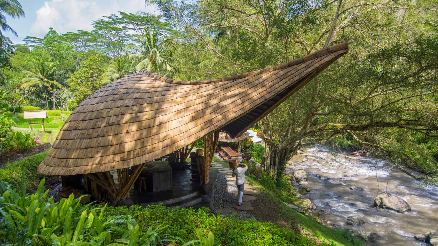 Small building with modern, extended roof overhang, next to river in Bali