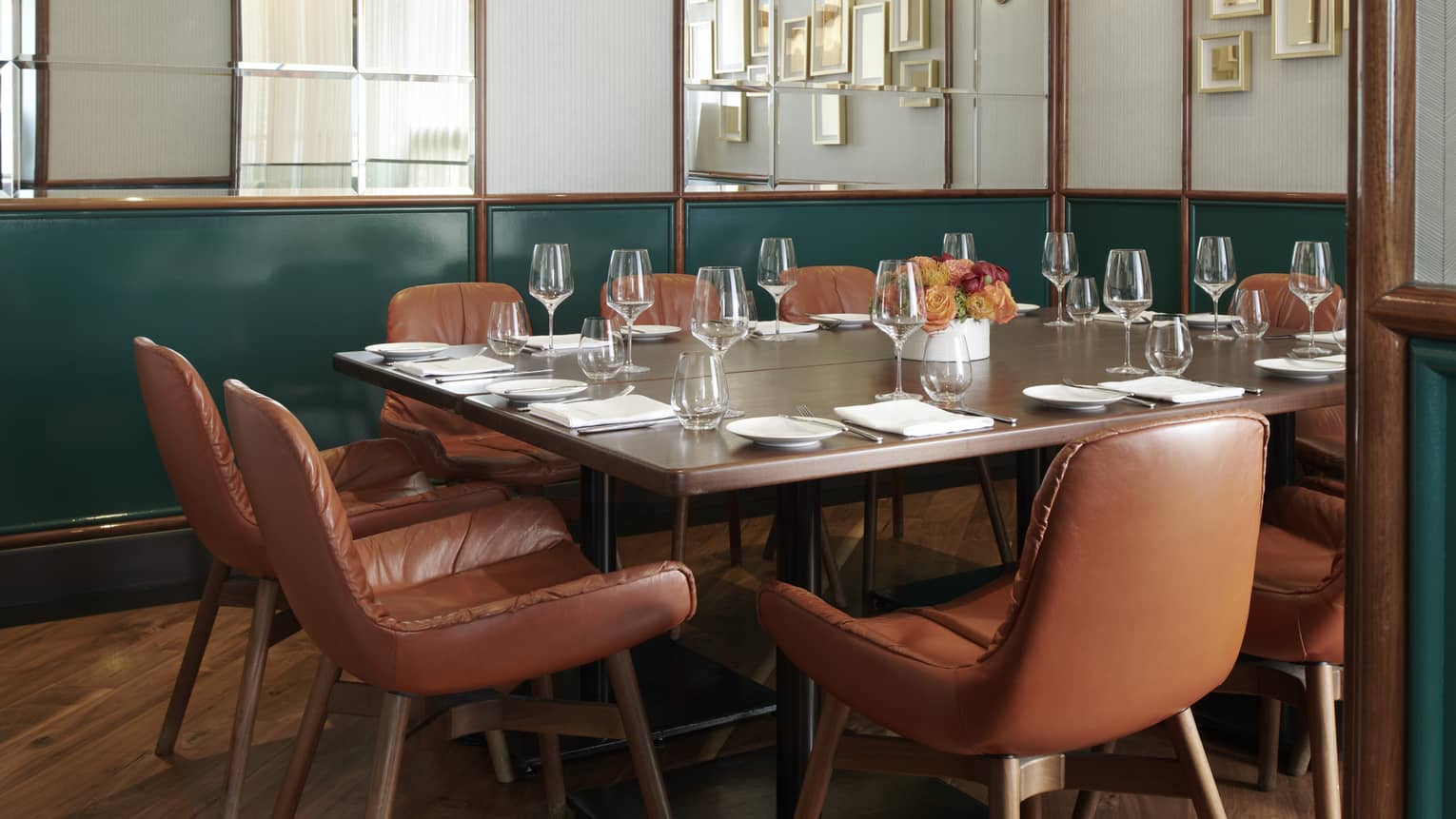 Private dining room with mirrored walls, dark green accents and a rectangular table with brown-leather seats