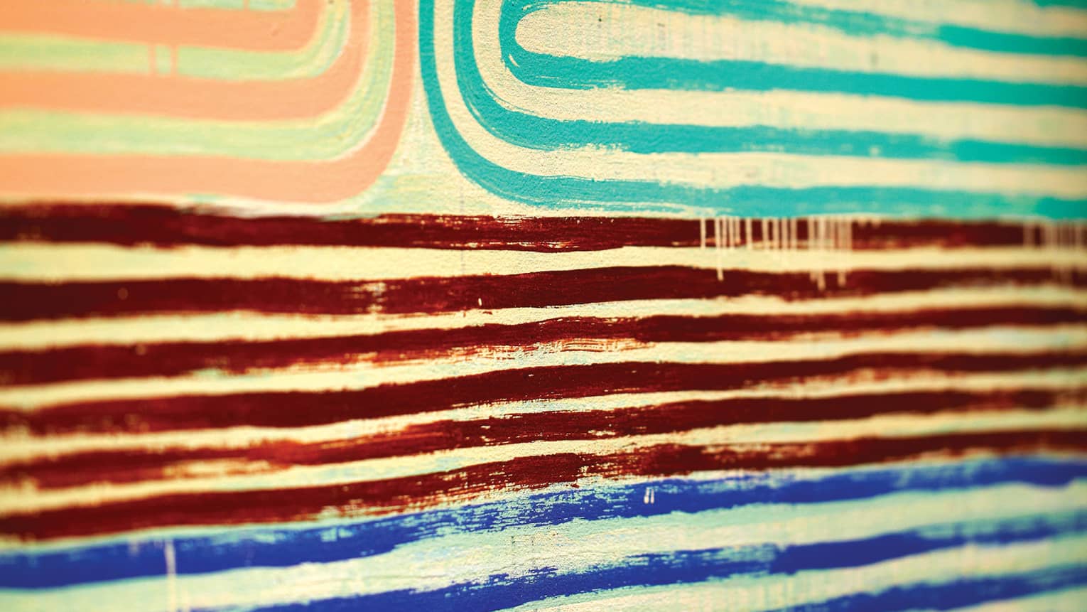 Close-up of pink, teal, red and blue lines of paint in pattern on canvas 