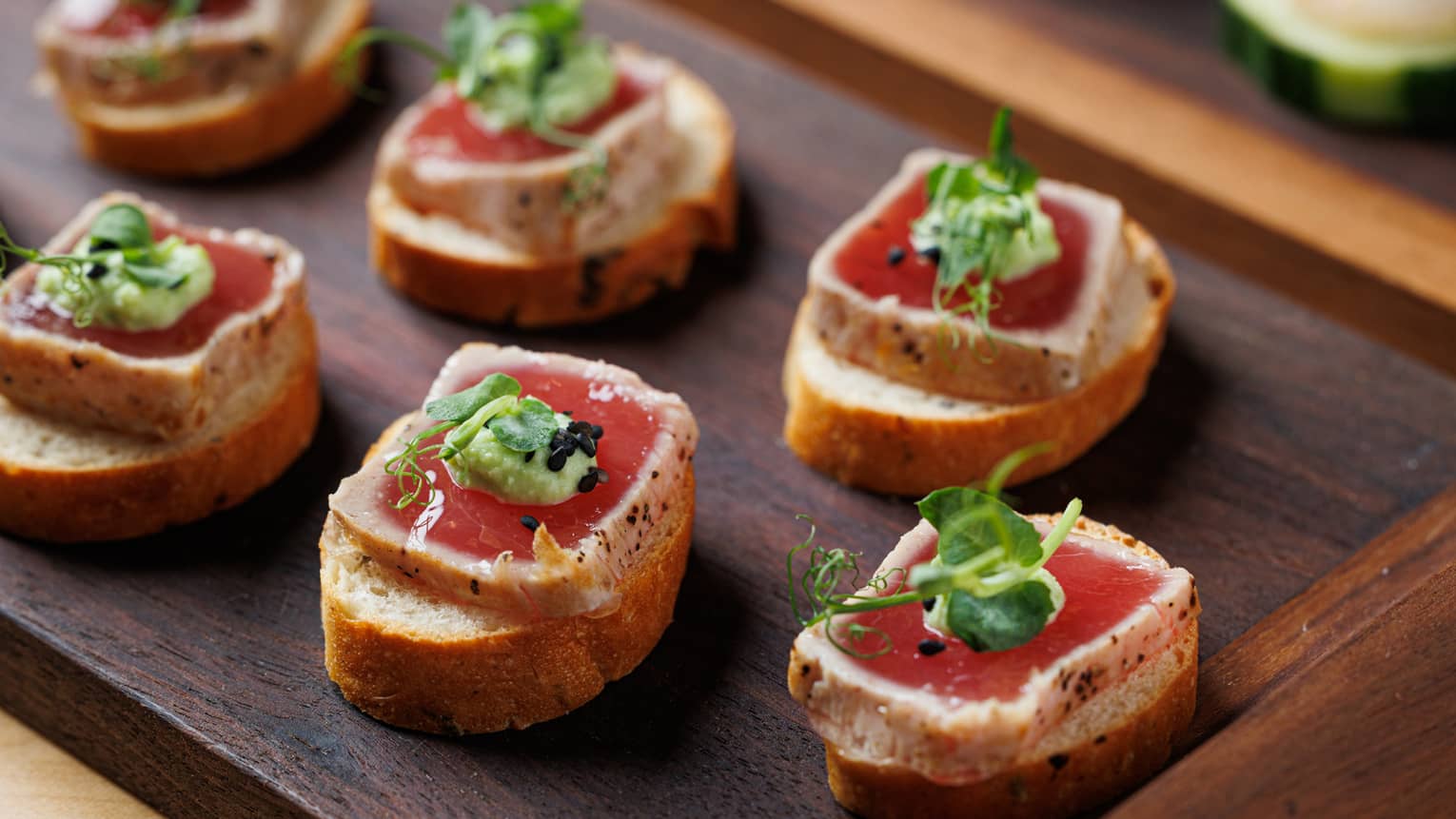Ahi tuna squares on bruschetta dotted with wasabi on wood tray