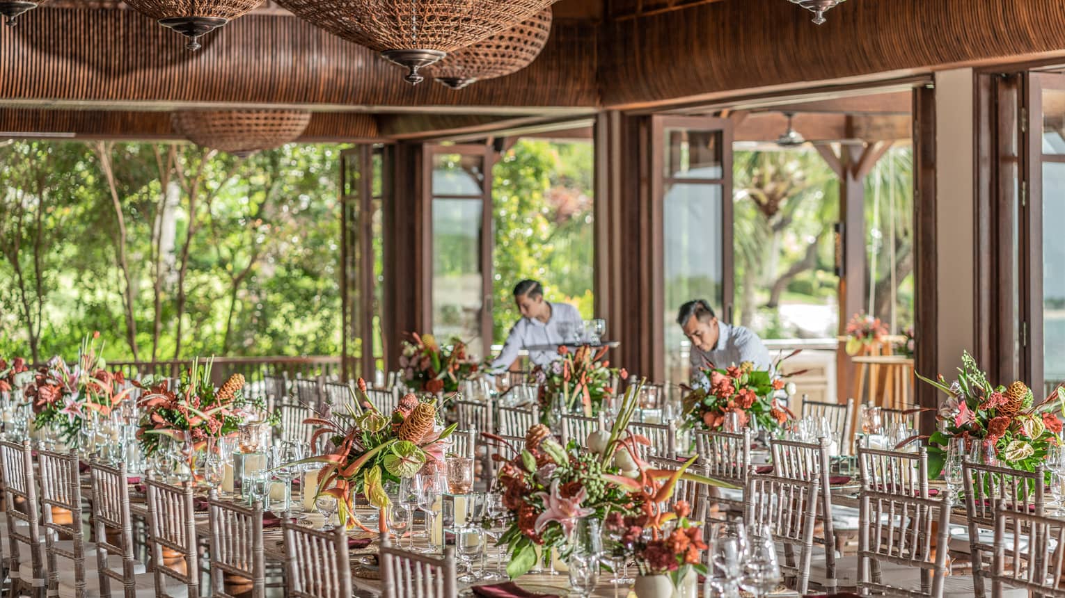 Employees set up florals and glasses on reception tables inside a mezzanine 