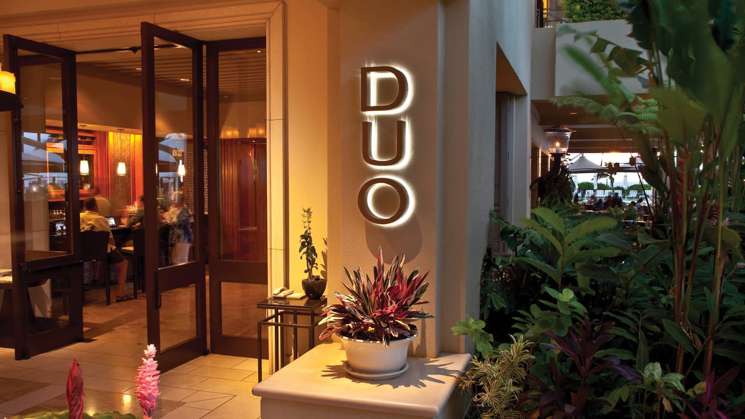 A view of the front door and reception at DUO Steak and Seafood, Four Seasons Resort Maui at Wailea, surrounded by local fauna