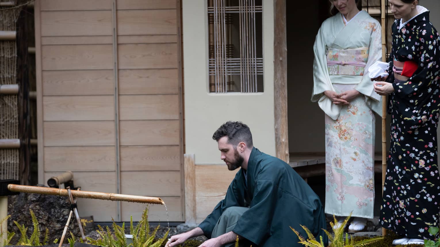 Couple in traditional Japanese dress learns to prepare tea for a tea ceremony outside the tea room