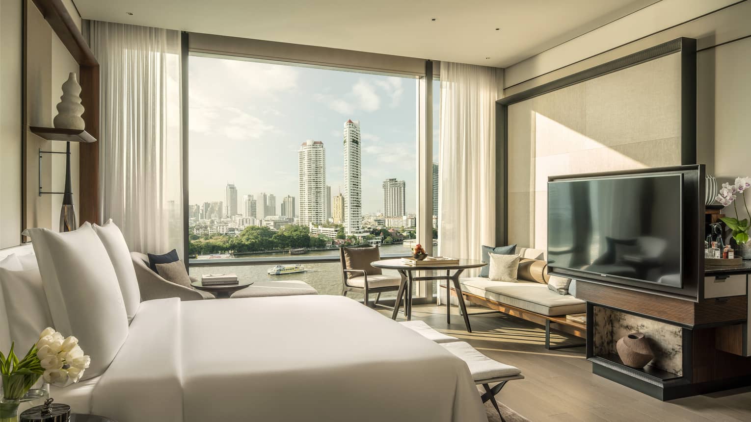 Hotel room with white king bed, view of Chao Phraya River, TV