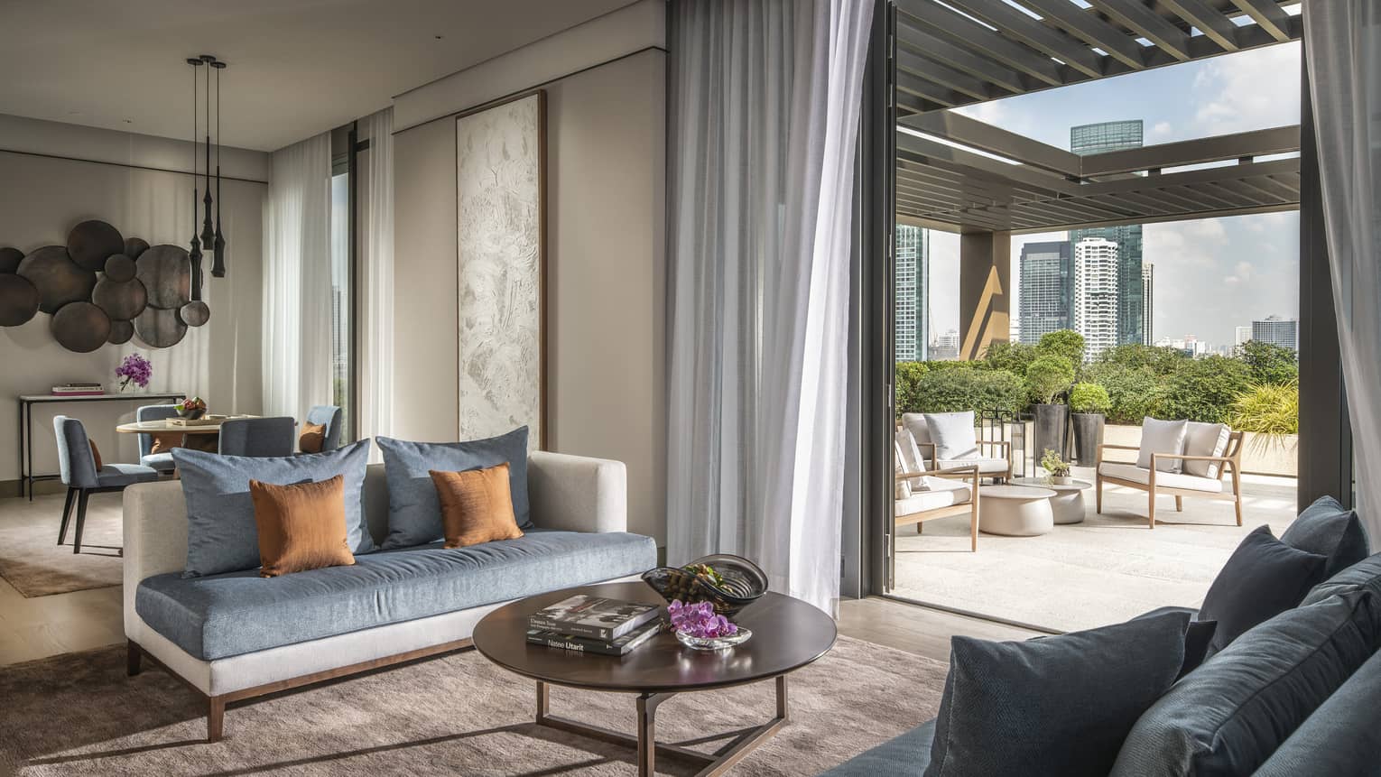 Hotel suite's living room opening up to a terrace with outdoor seating