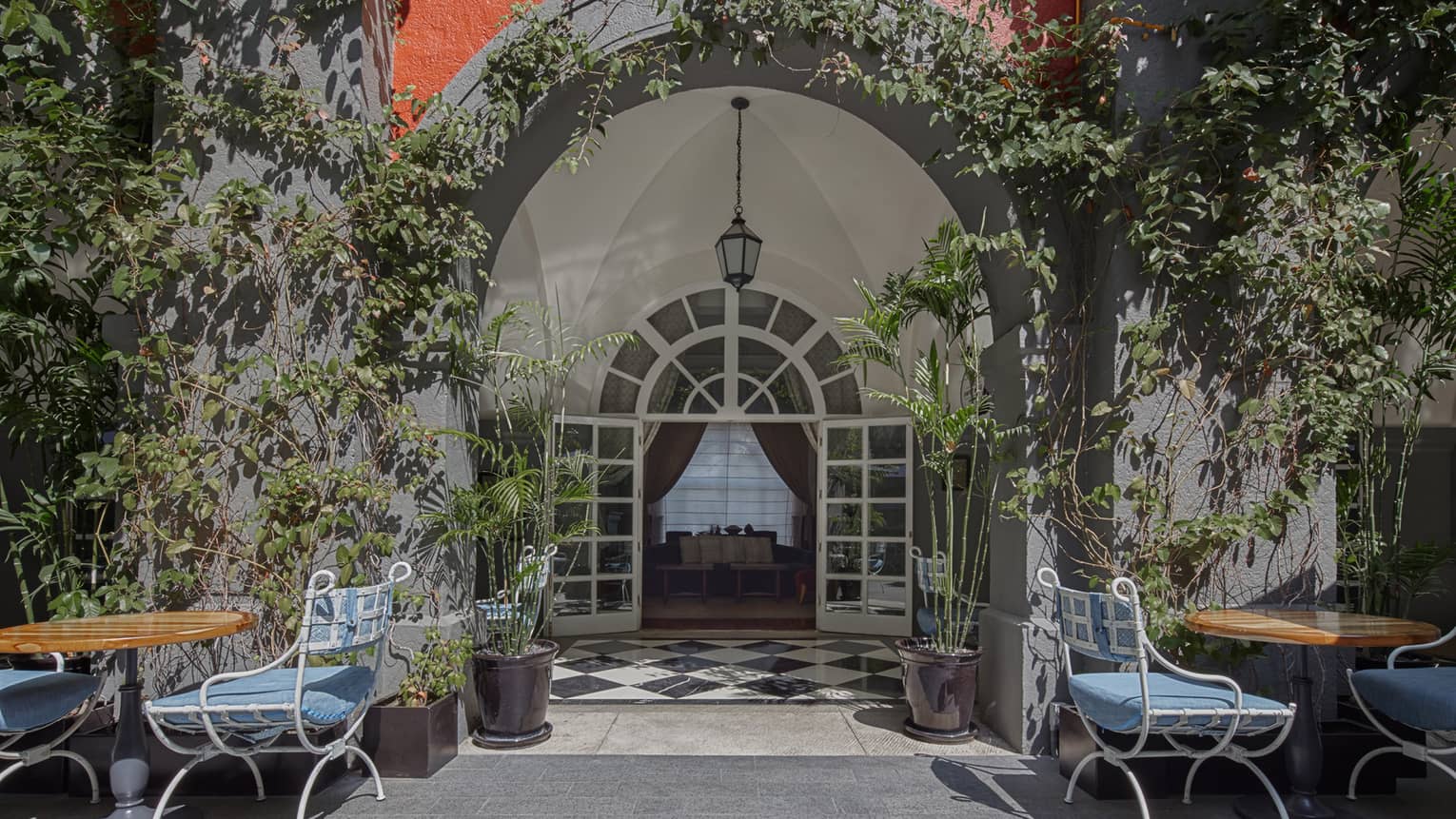 Outdoor dining tables underneath an archway in the courtyard of Four Seasons Hotel Mexico City